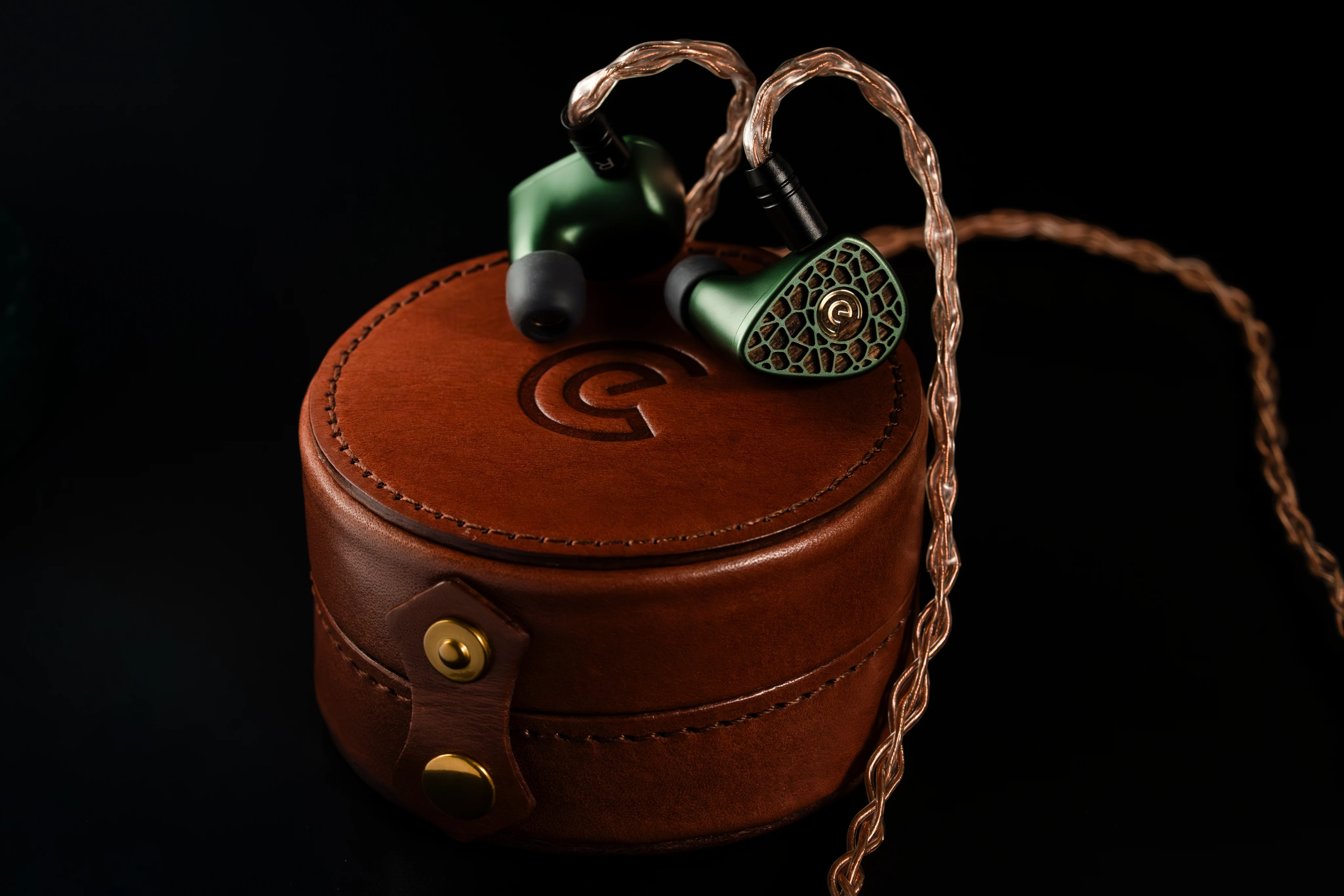 Leszy resting on its round brown leather case with an embossed Craft Ears logo